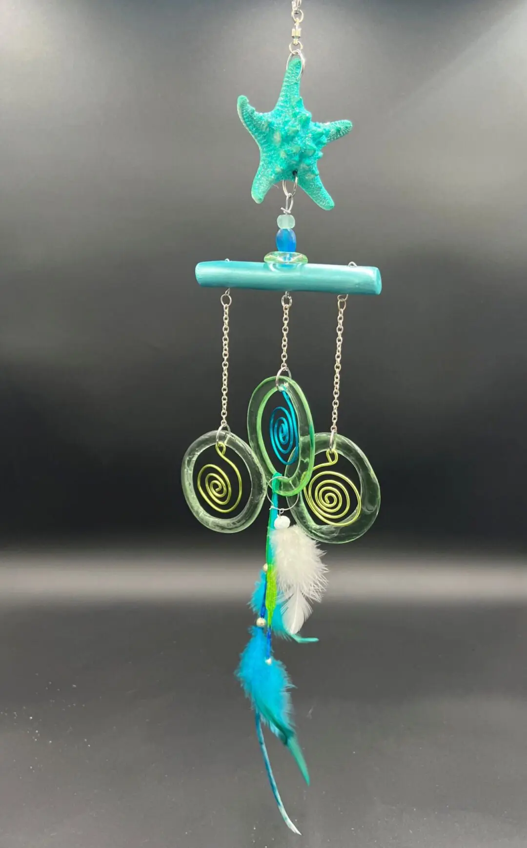 Starfish-themed mobile with feathers and spirals.