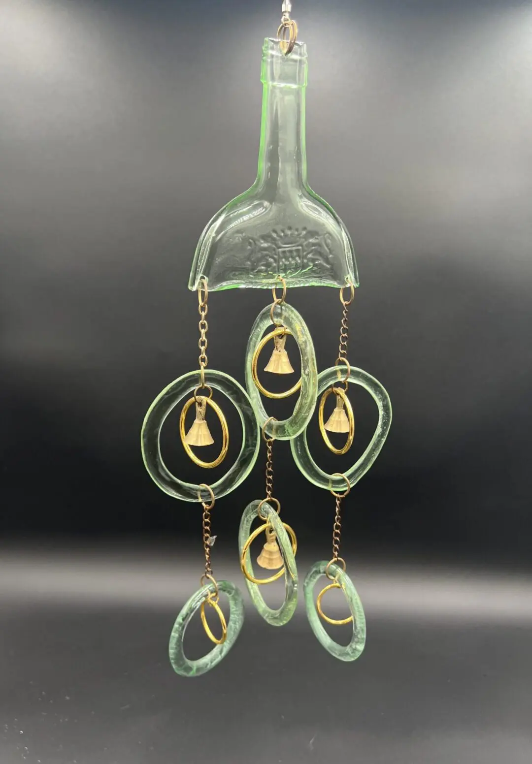 Glass bottle wind chime with circular ornaments.