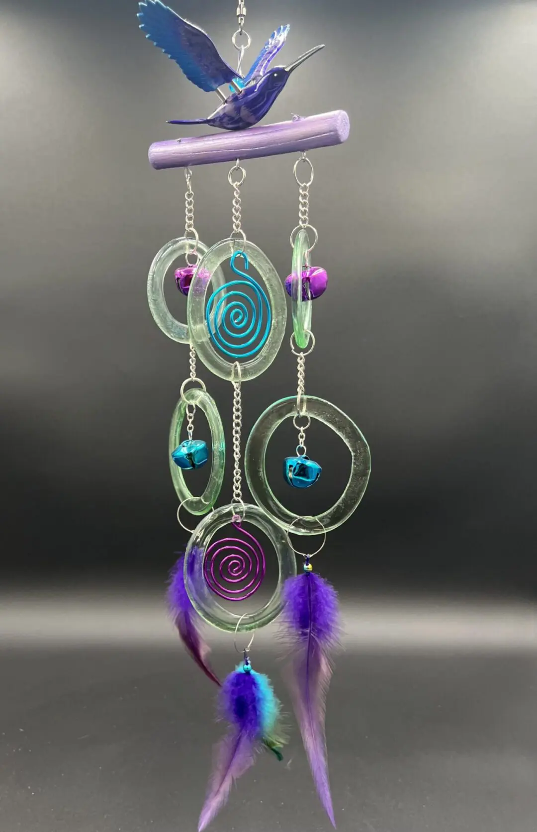 Hummingbird wind chime with colorful feathers.